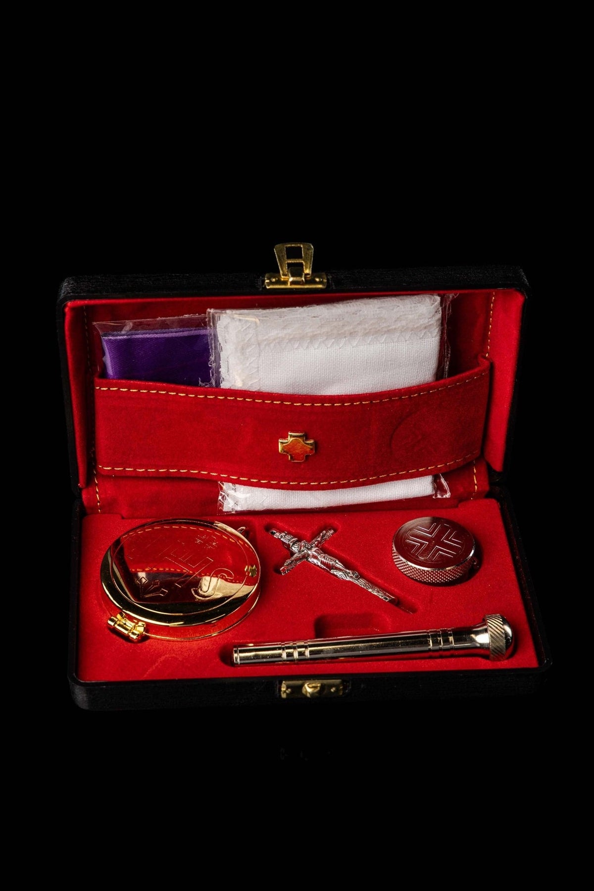 Open liturgical supplies burse with red interior, gold trim, crucifix, pyx and aspergillum