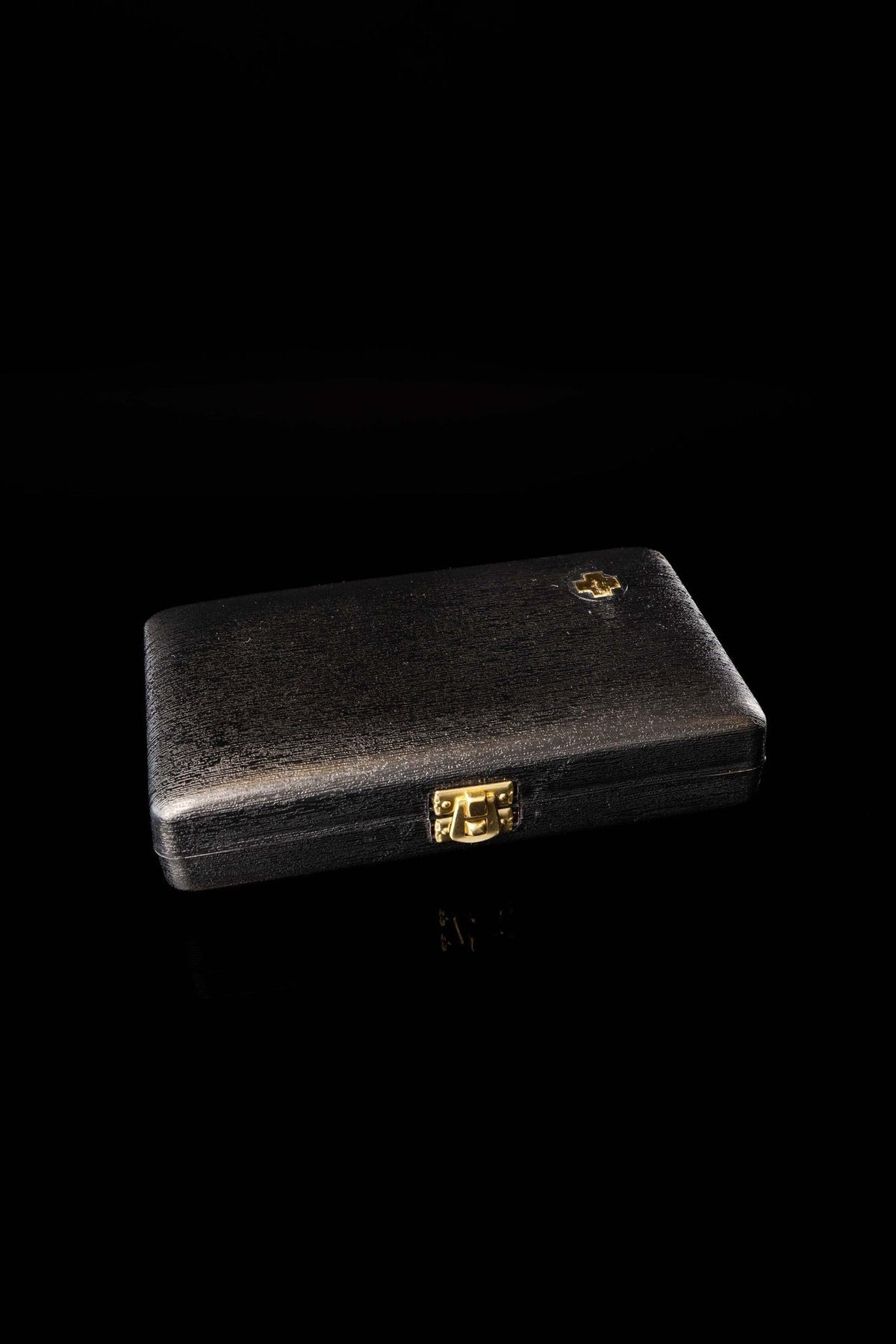Closed black liturgical supplies burse with gold clasp and small cross emblem