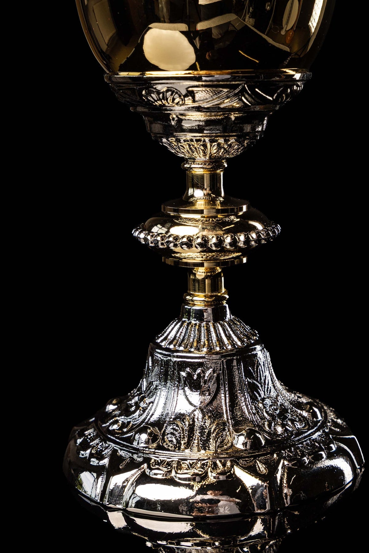 Gold and silver chalice close-up showing the decorated cup, stem, and upper base