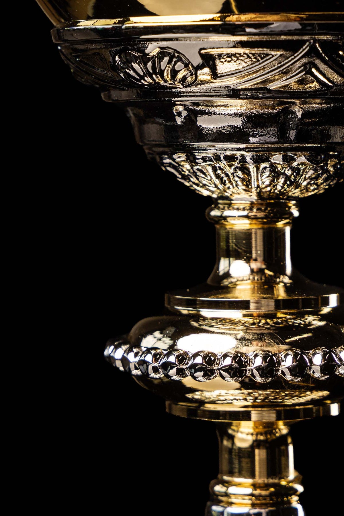 Gold and silver chalice detail showing the fluted stem and decorative relief on the base