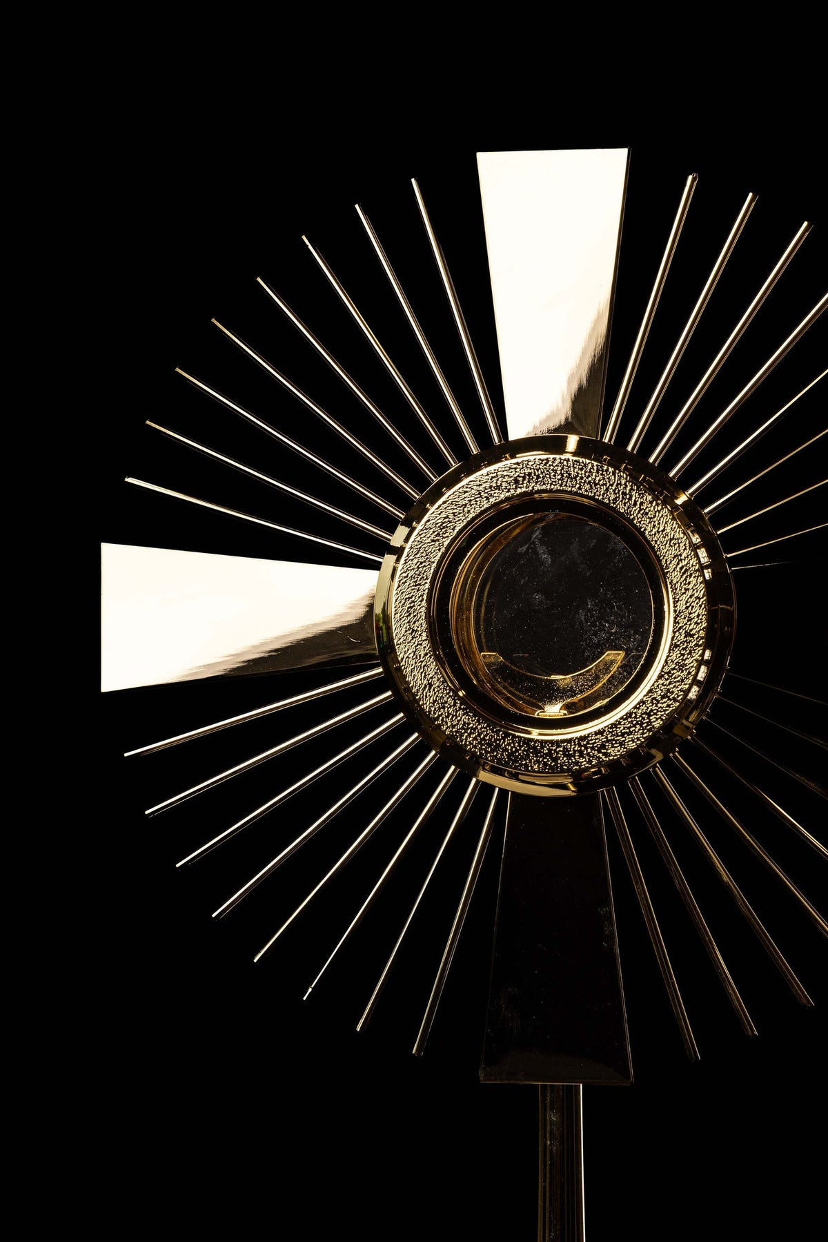 Gold-plated brass monstrance close-up showing the radiating rays and cross motif