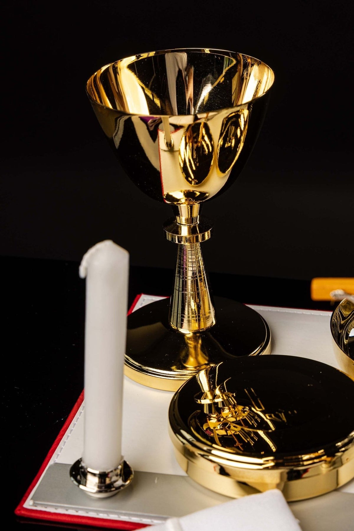 Mission case gold chalice shown close-up beside candle and paten