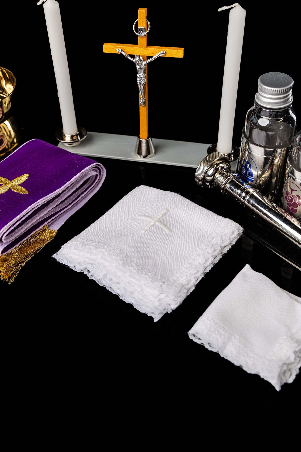 Close-up of liturgical suitcase altar set with crucifix, candles, bottles and white linens