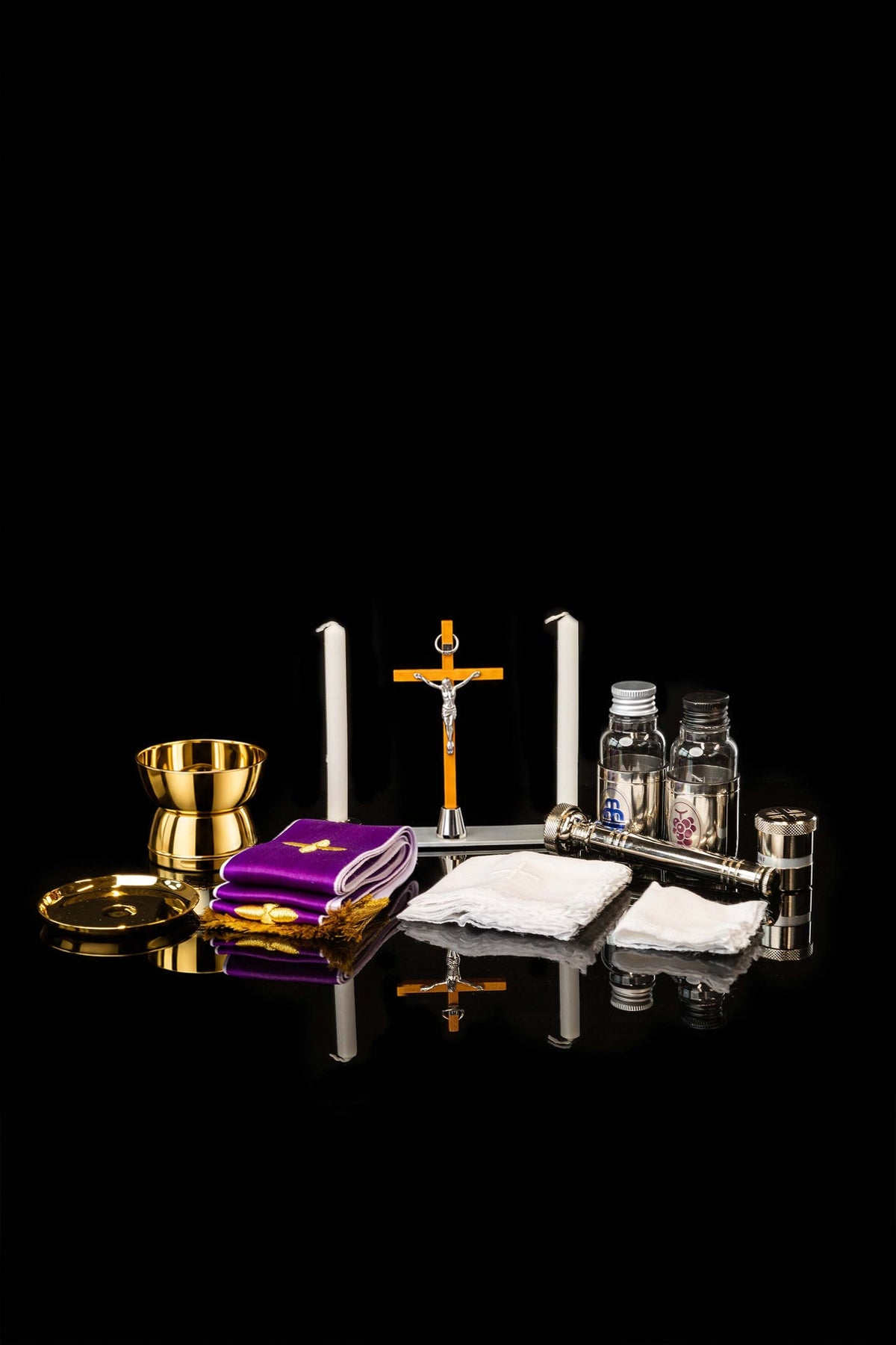 Liturgical equipment suitcase contents arranged with gold vessels, candles, crucifix and purple cloths