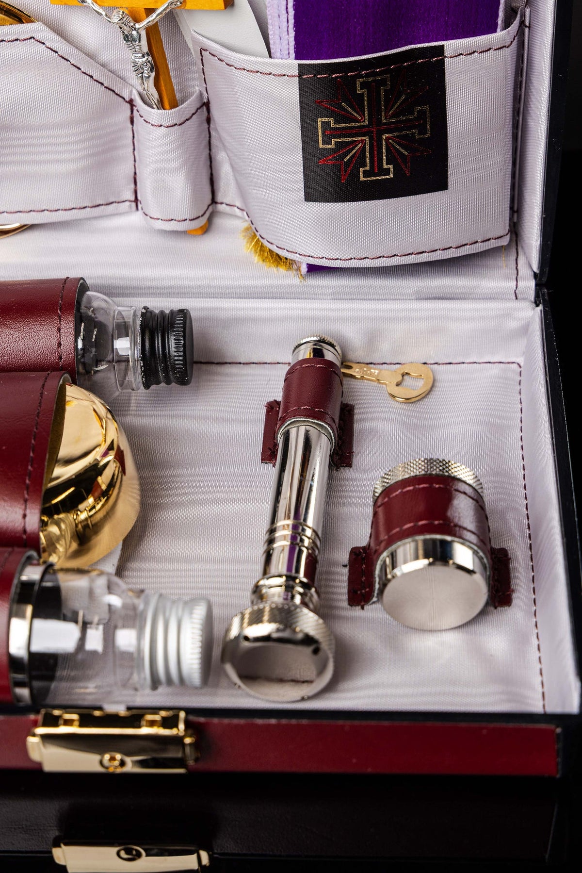 Close-up of liturgical suitcase with silver liturgical tools, bottles and burgundy holders