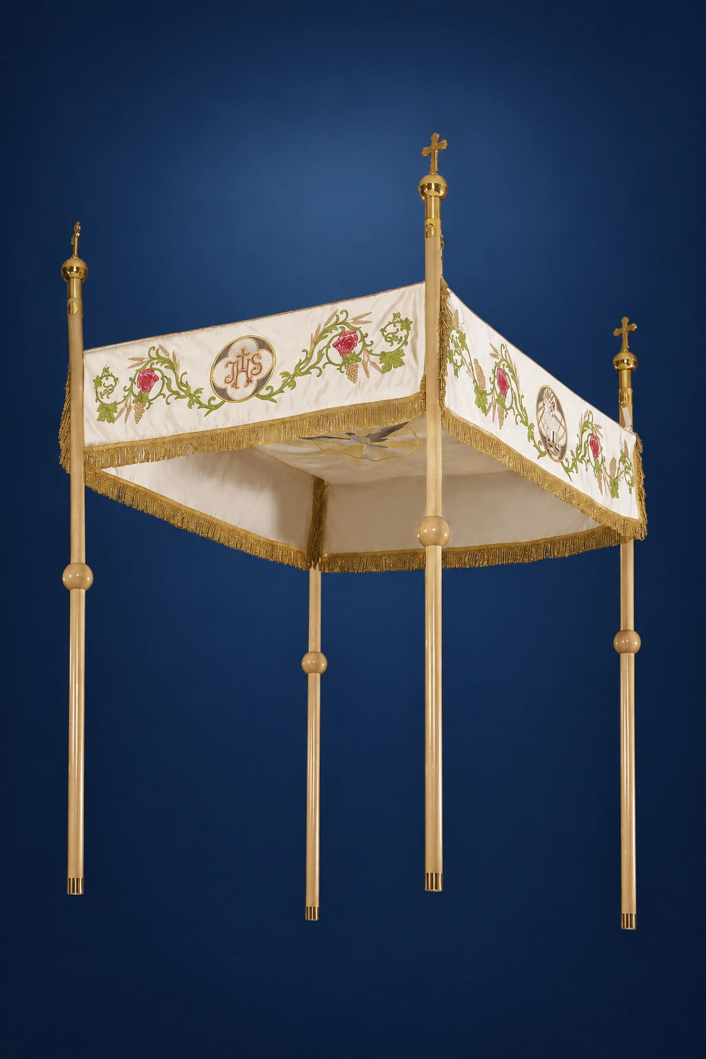 Ecru Corpus Christi canopy with floral and IHS embroidery, trimmed in gold fringe, shown in three-quarter view