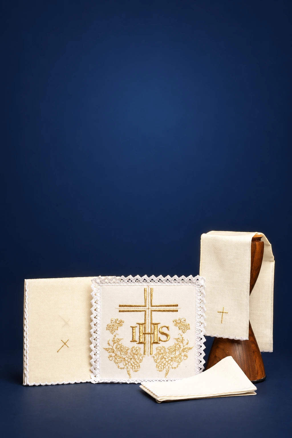 Embroidered altar linen set with central IHS cross, scalloped edge cloth, and folded linens with small crosses