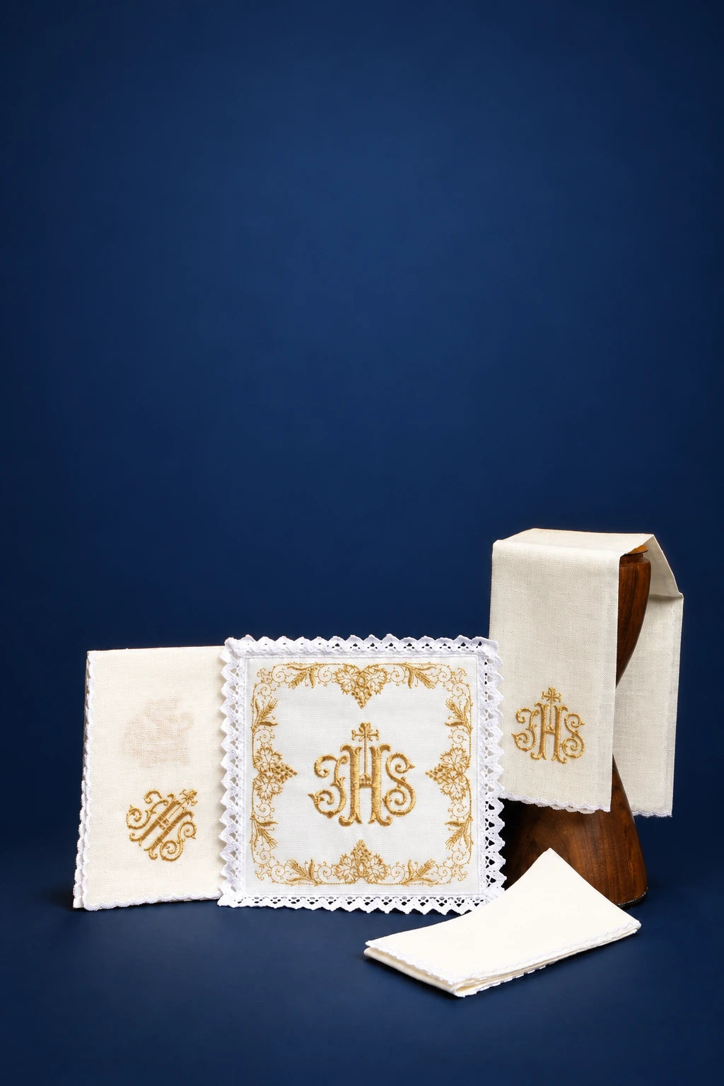 Embroidered linen altar linen set with IHS monogram, shown with folded corporal, purificator, and veil pieces