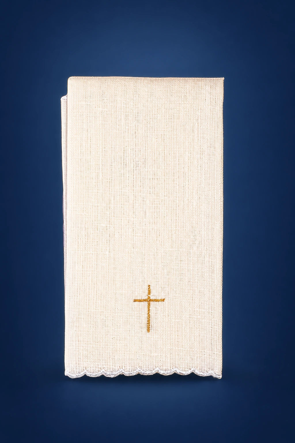 Folded white linen purificator with small gold cross and scalloped hem