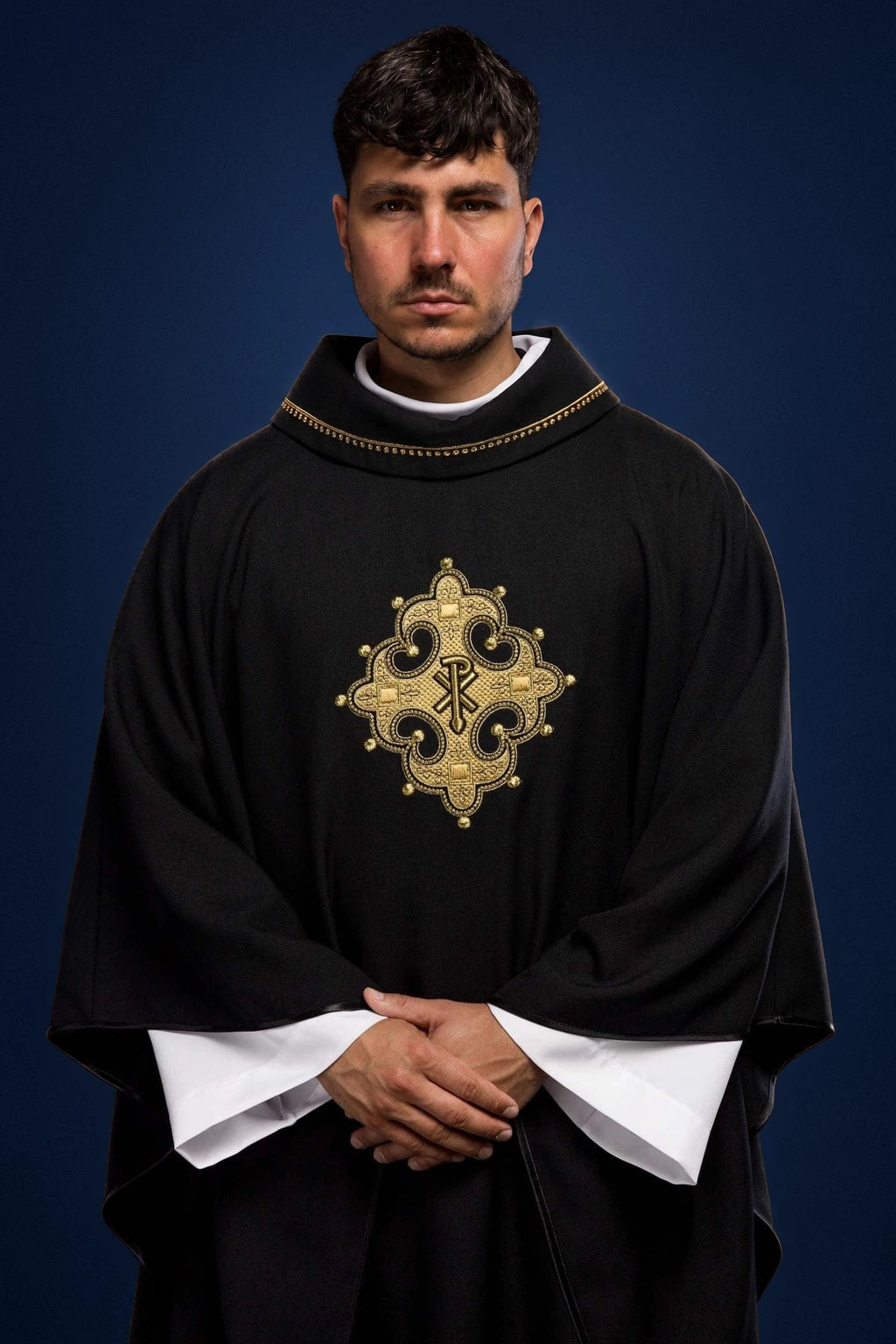 Front view of a black chasuble with gold collar trim and embroidered cross medallion.