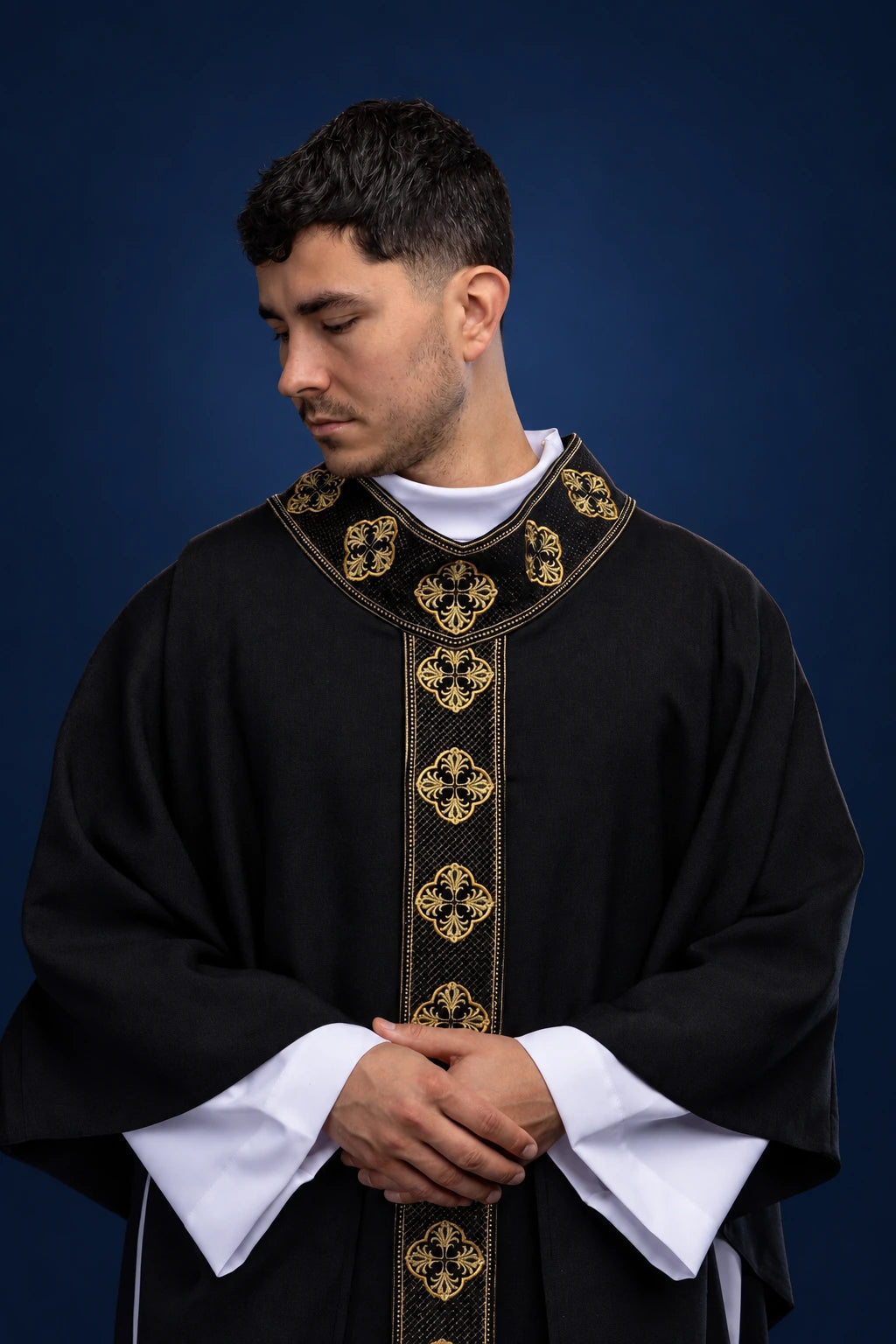 Front view of a black chasuble with gold embroidered orphrey and collar cross motifs
