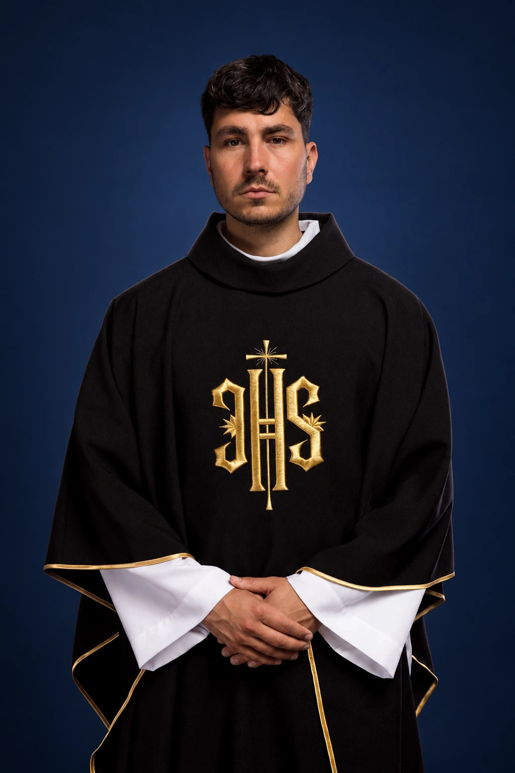Front view of black chasuble with gold IHS embroidery and gold-trimmed edges