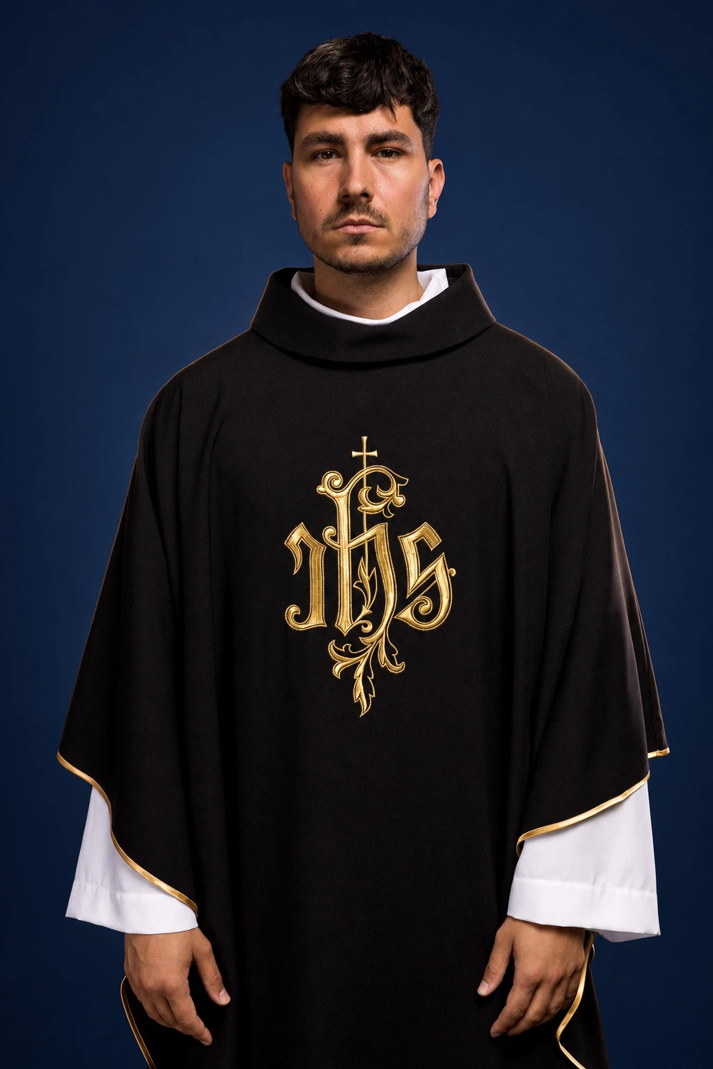Front view of a black chasuble with gold IHS embroidery and gold-trimmed edges