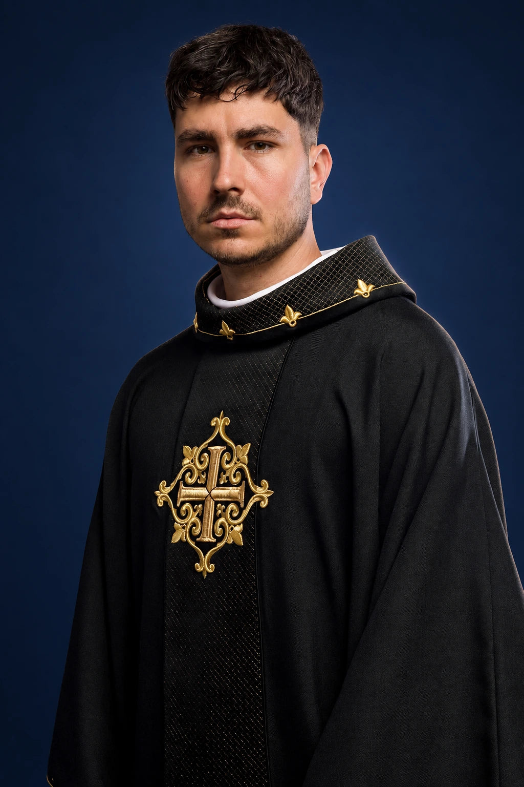 Front view of a black velvet chasuble with gold embroidery and a black cross symbol on the chest