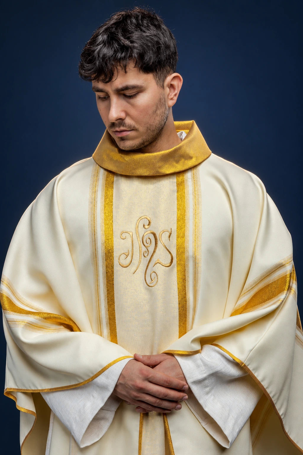 Front view of cream chasuble with gold collar, vertical trim, and embroidered IHS monogram
