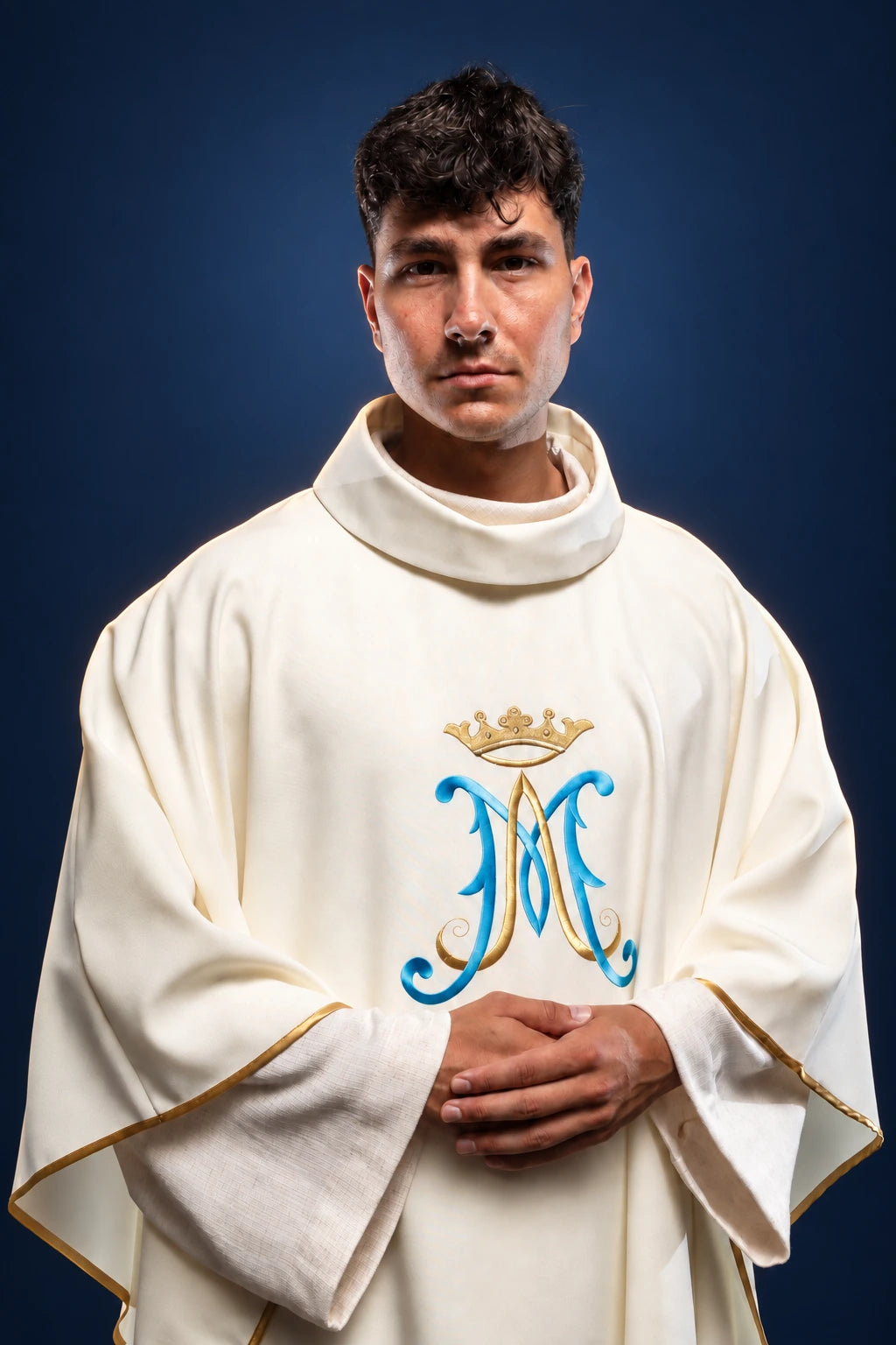 Front view of an ecru chasuble with blue and gold crowned Marian monogram and gold edging