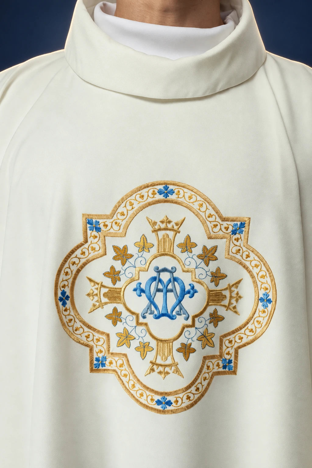 Front view of an ecru chasuble with embroidered Marian emblem on the chest and folded inner stole collar