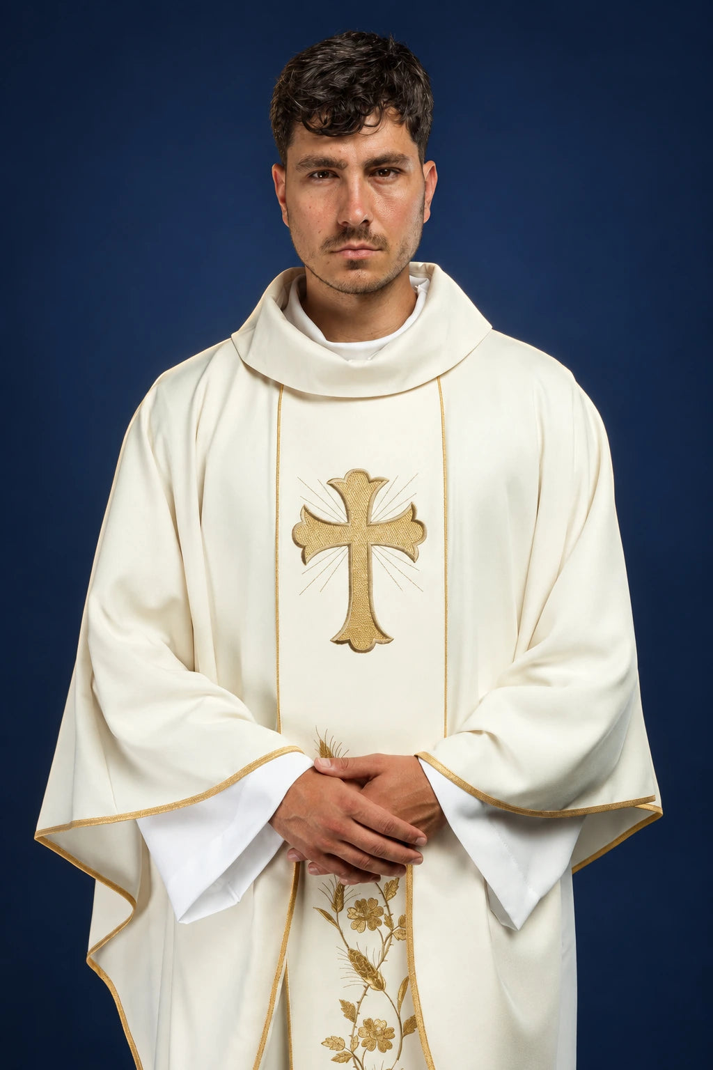 Front view of an ecru chasuble with gold cross and wheat embroidery, worn over a white alb