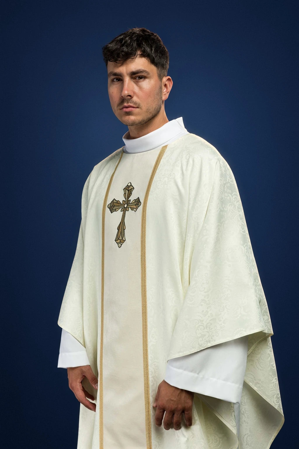 Front view of an ecru chasuble with gold orphrey and embroidered cross motif.