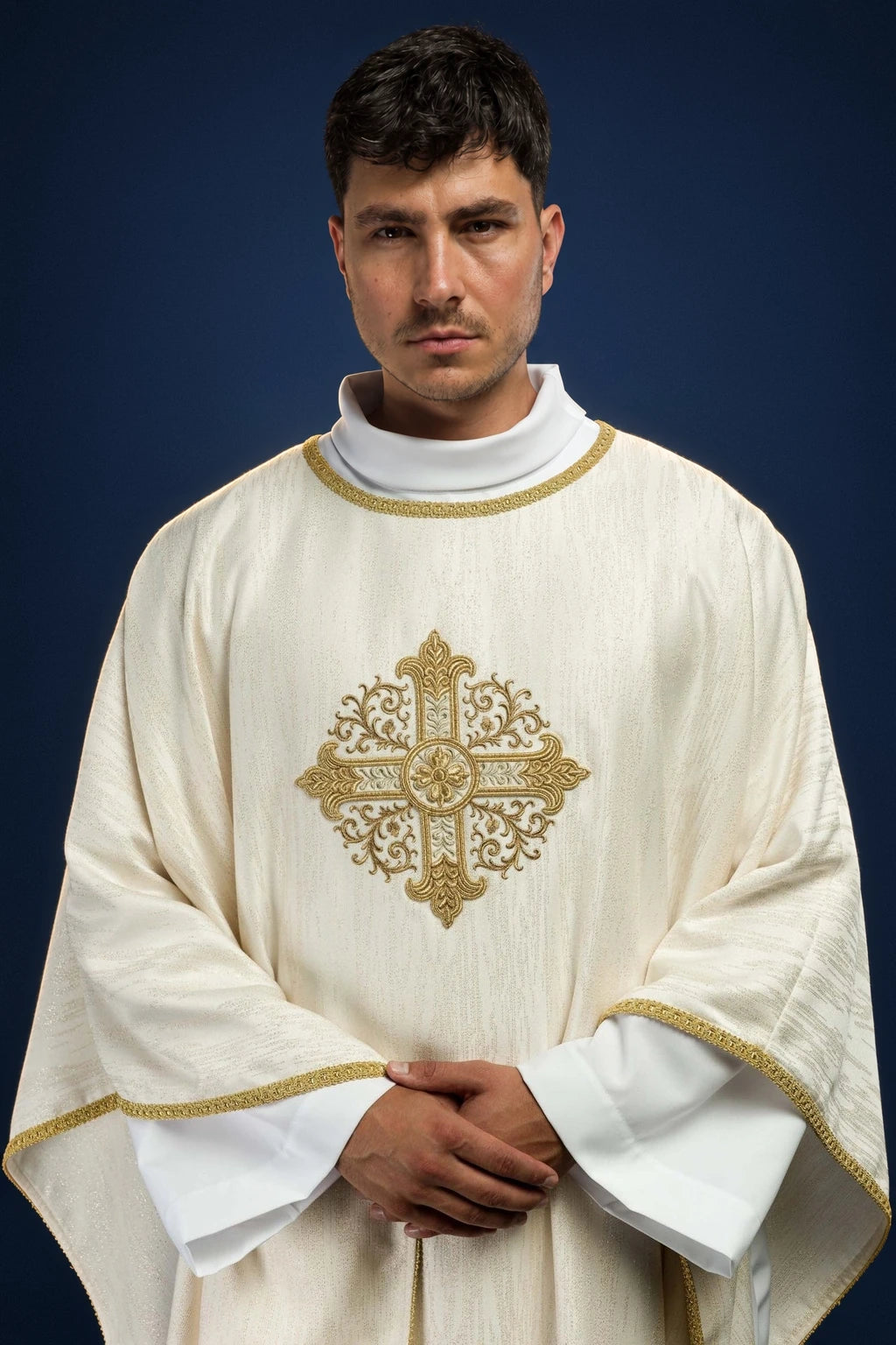 Front view of an ecru chasuble with gold trim and embroidered cross motif on the chest