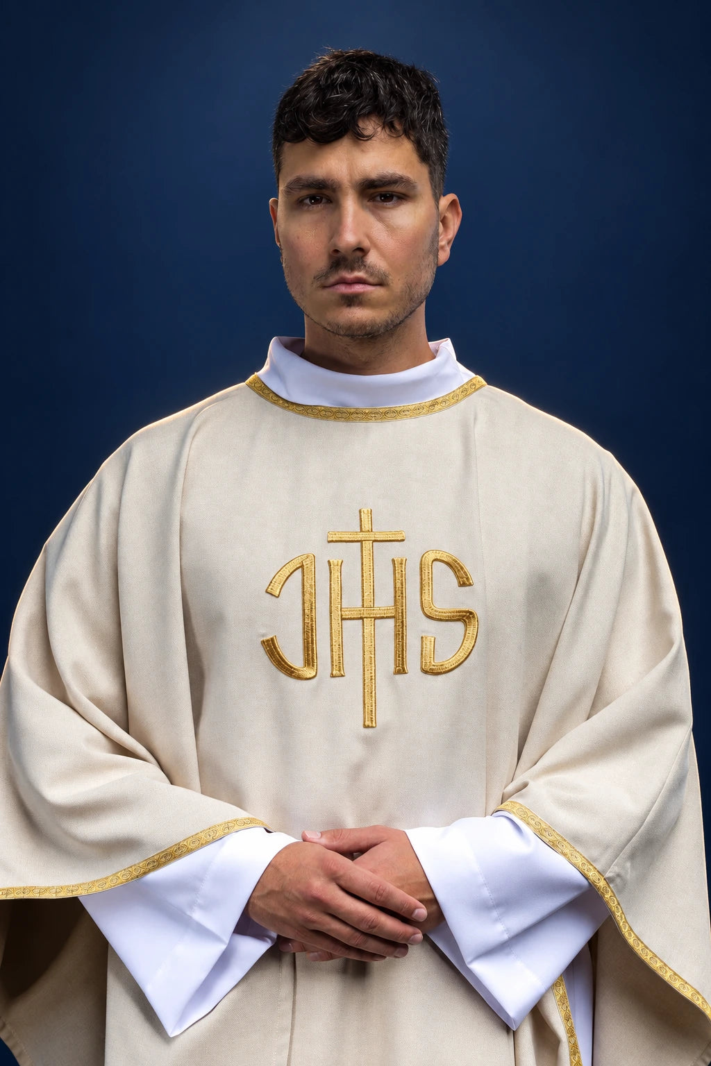 Front view of an ecru chasuble with gold trim and large gold IHS embroidery on the chest