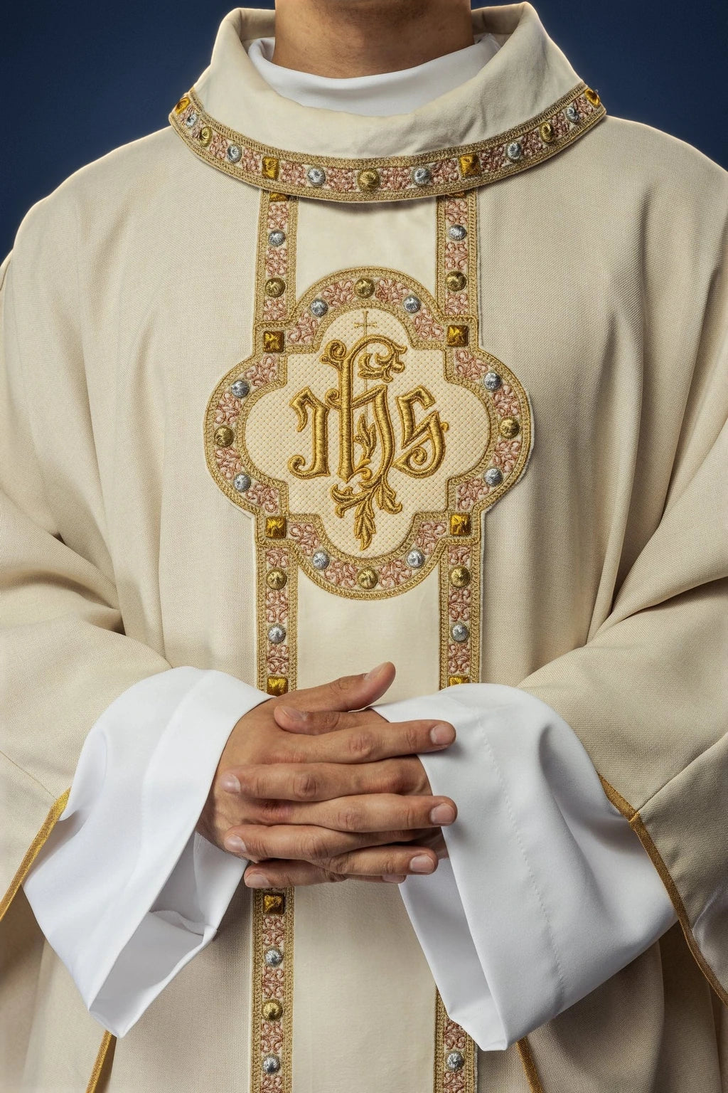 Front view of an ecru chasuble with ornate embroidered orphrey and large IHS medallion trim