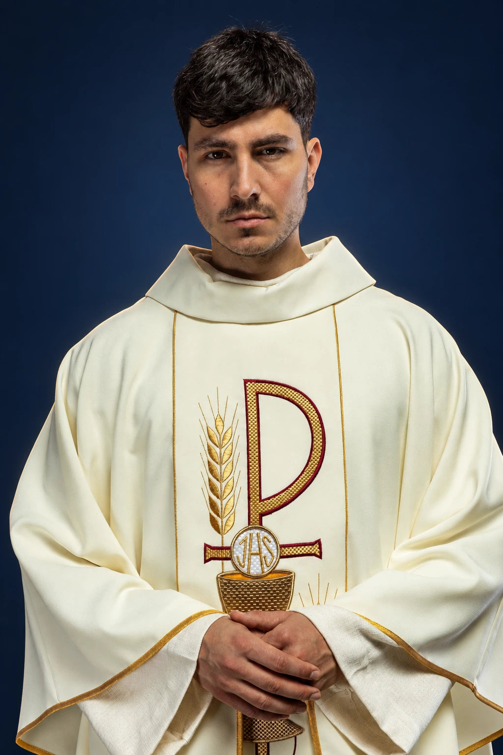 Front view of an ecru chasuble with wide collar and embroidered IHS chalice motif on the chest