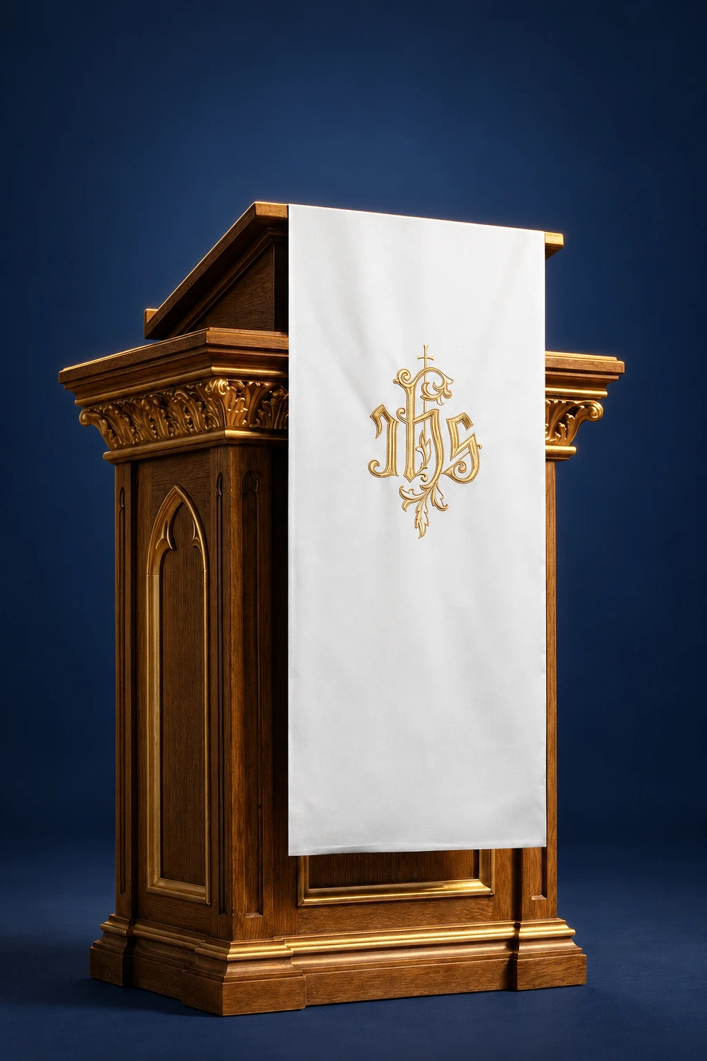 Front view of an ecru lectern cover with embroidered gold IHS symbol, hanging over the pulpit front