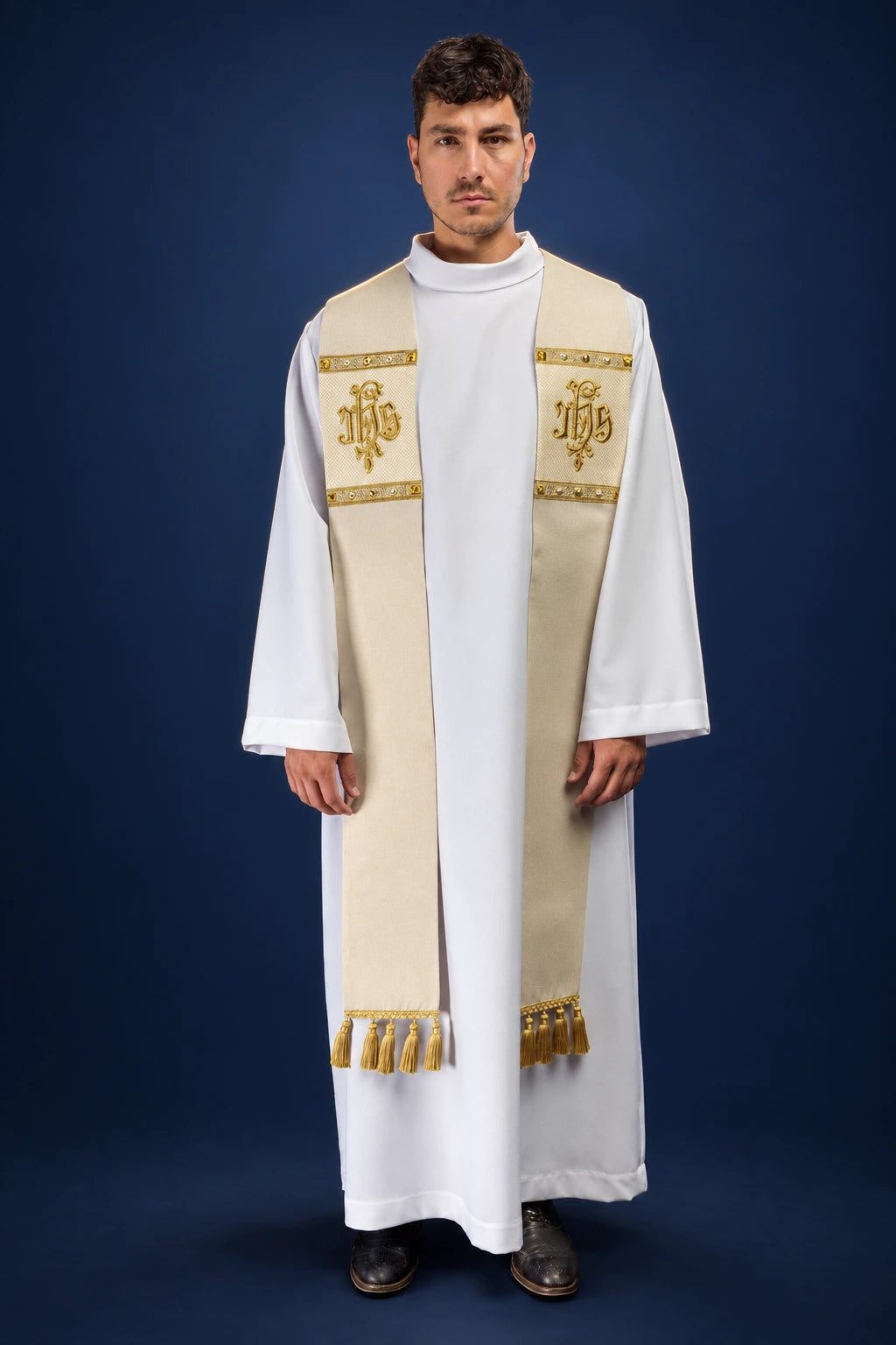 Front view of an ecru stole with gold IHS embroidery and tassels, worn over a white alb.