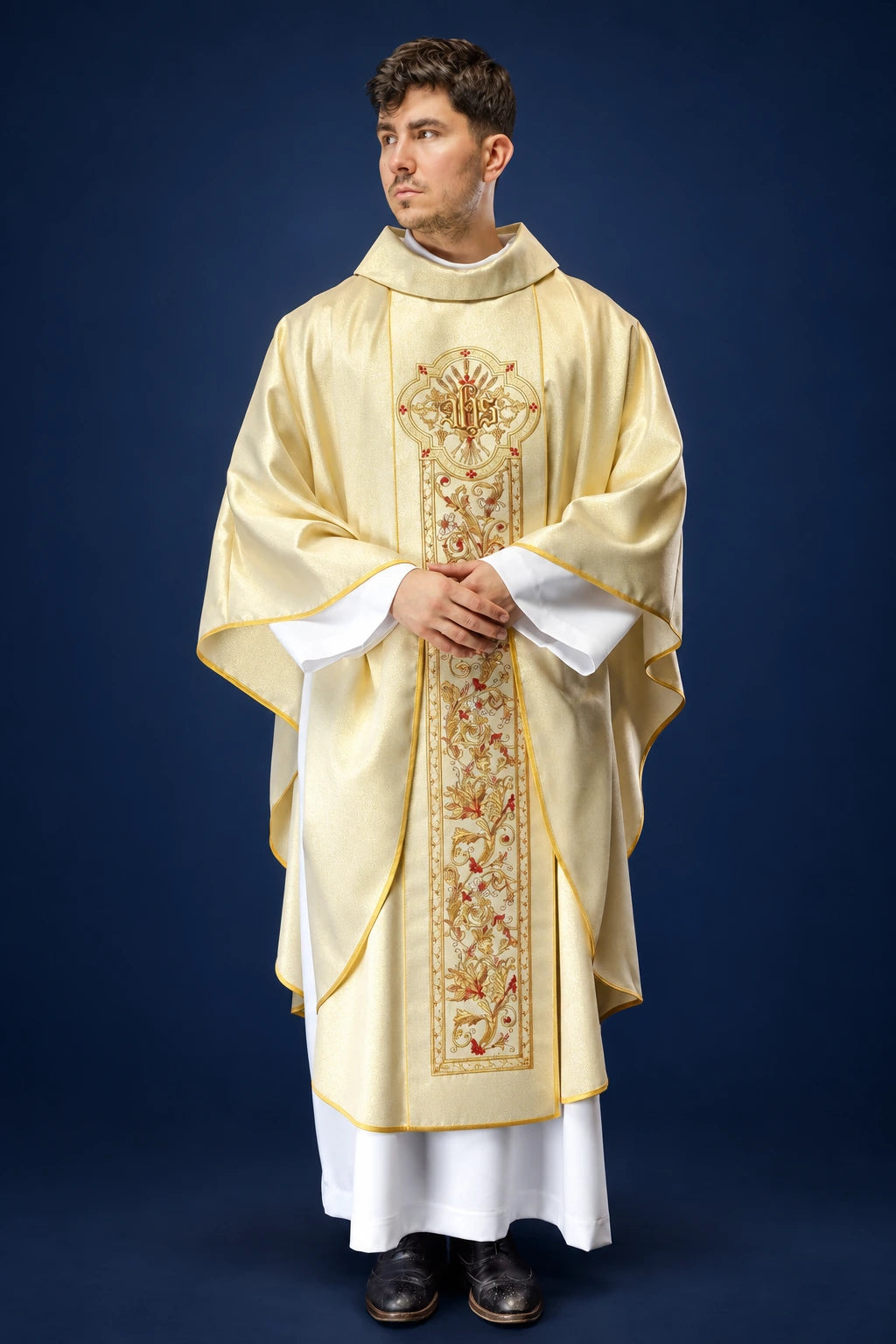 Front view of a gold chasuble with wide gold trim and an ornate central IHS panel