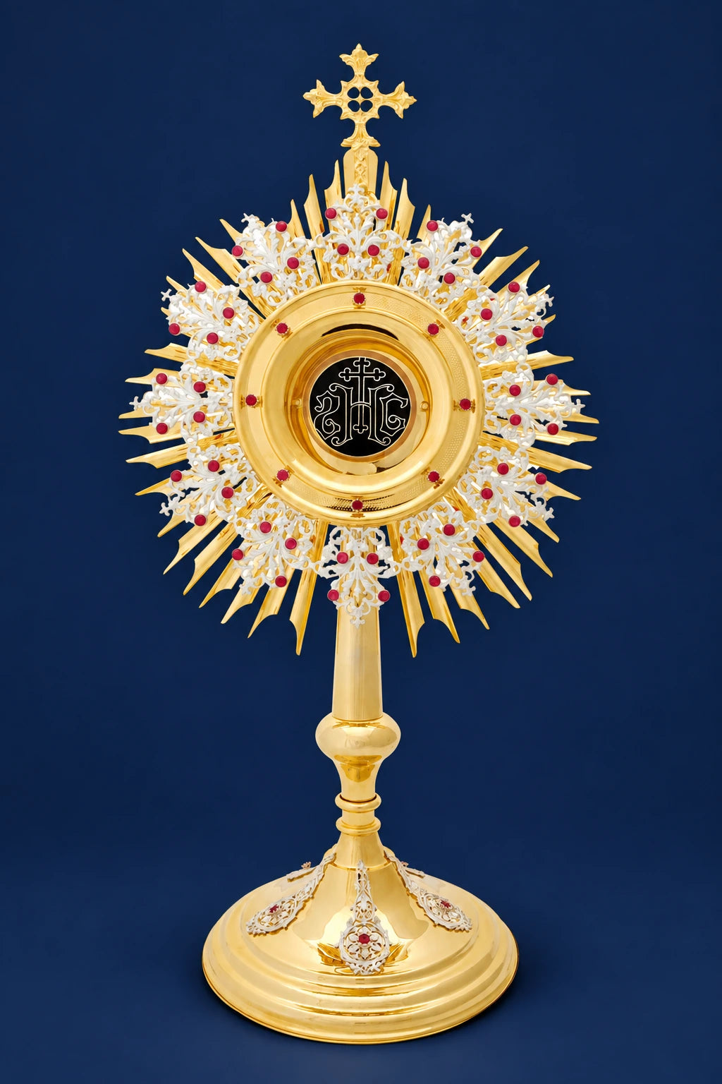 Front view of a gold-plated brass monstrance with radiating rays, rubies, and a decorative base