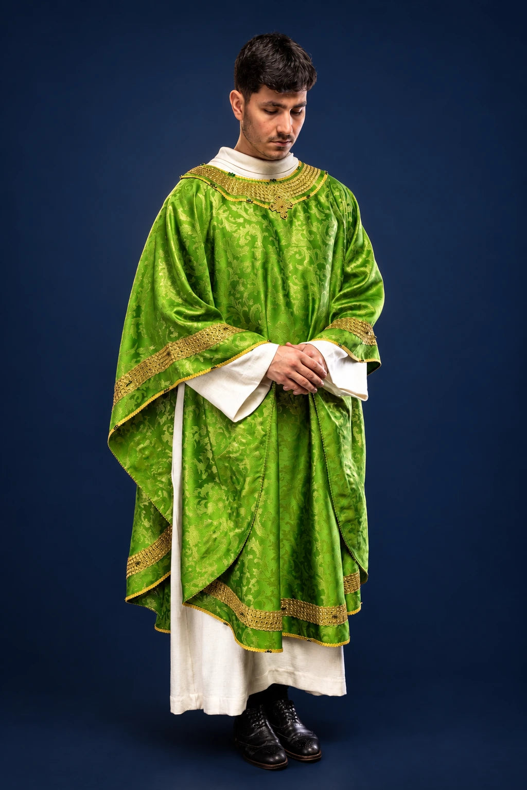 Front view of a green chasuble with gold trim and natural stone detailing over a white alb