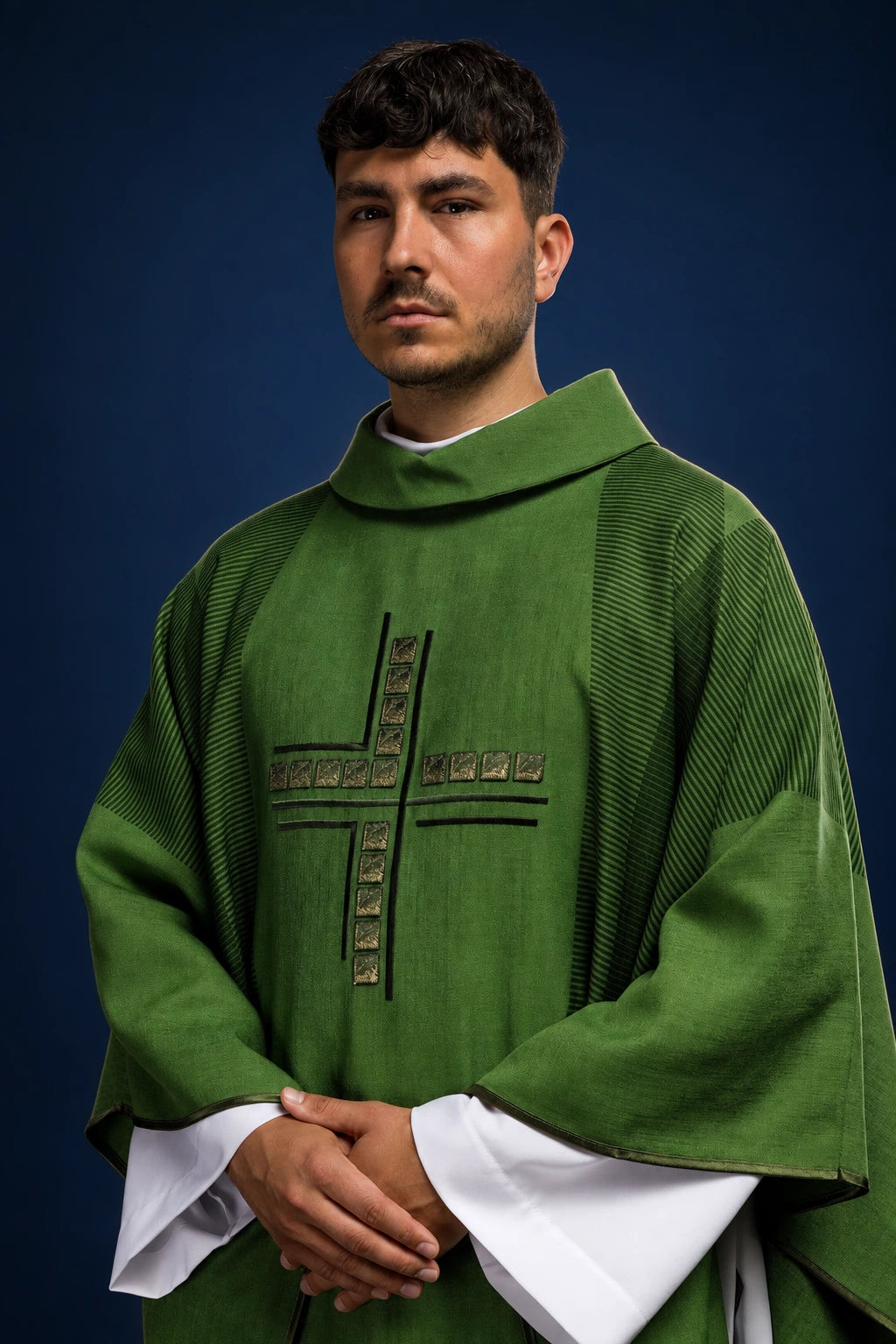 Front view of a green chasuble with a striped cross embroidery and wide draped sleeves