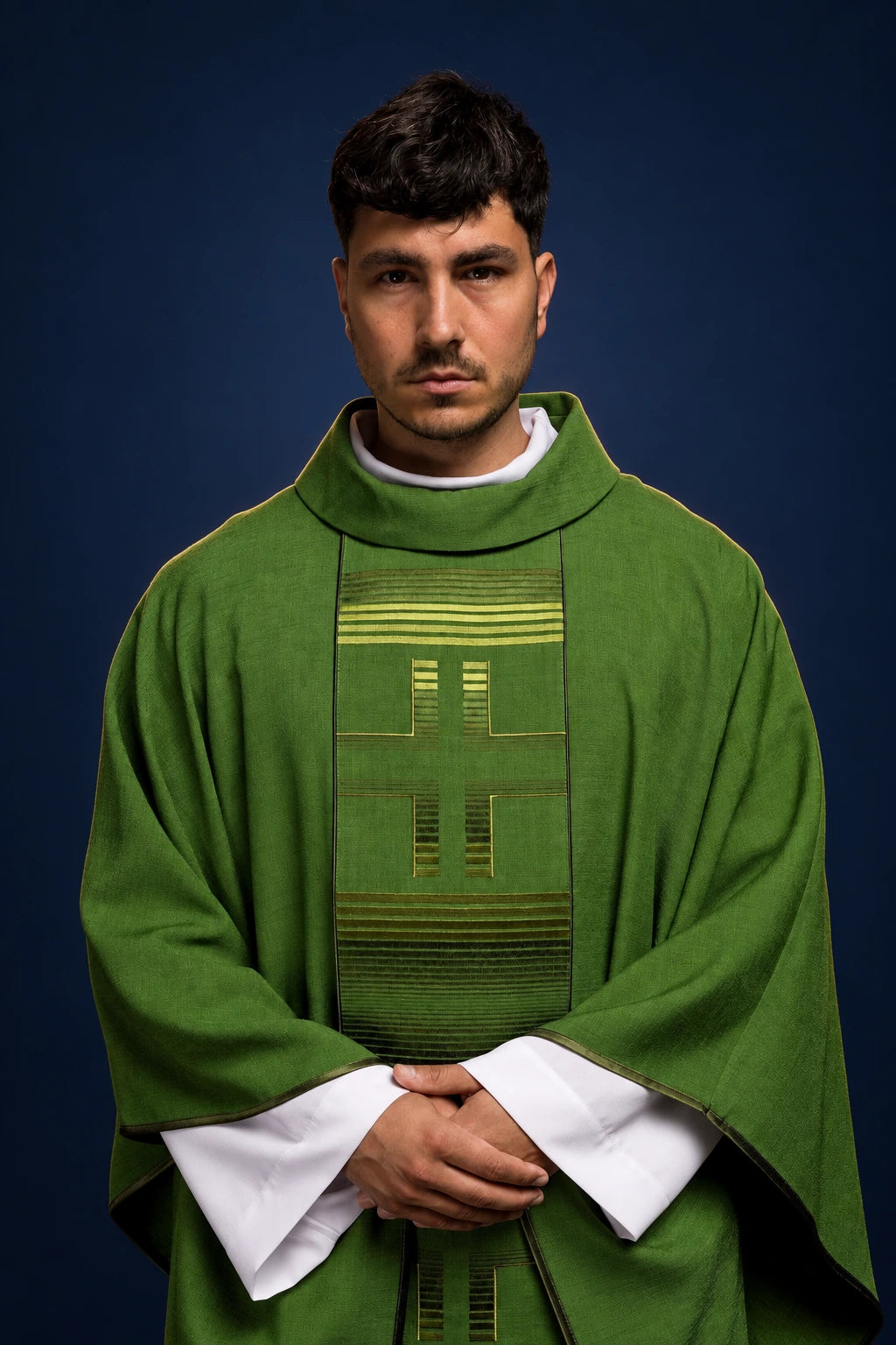 Front view of a green chasuble with vertical embroidered panel and three crosses, worn over a white alb