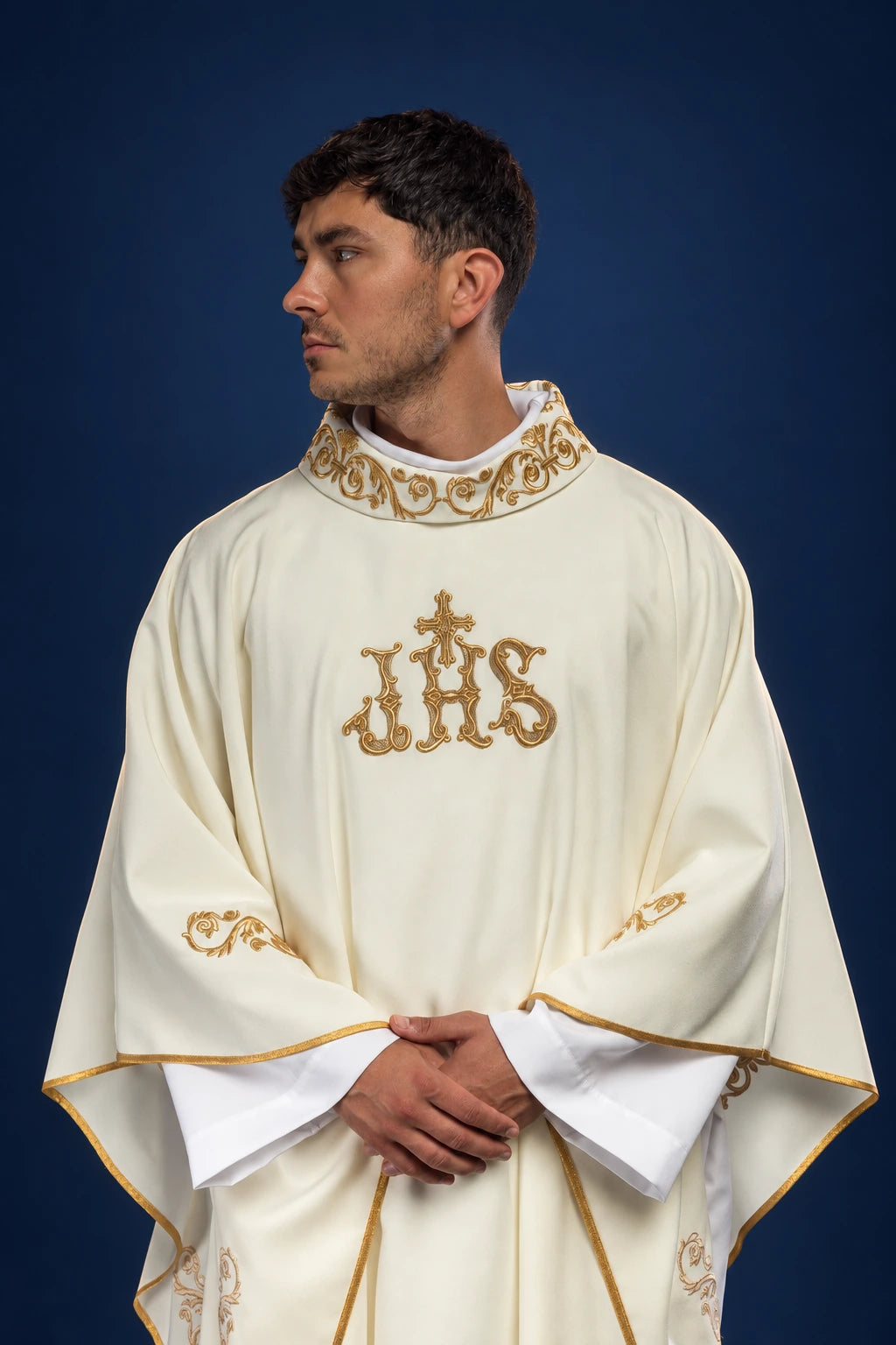 Front view of ivory chasuble with gold decorative trim and central IHS motif