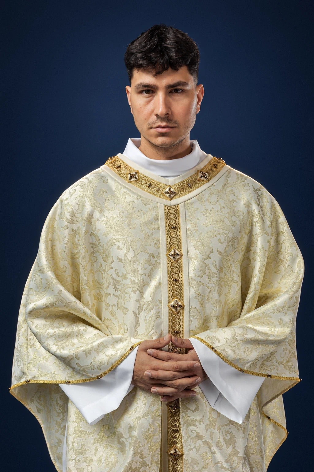Front view of an ivory chasuble with gold trim, central vertical band, and floral brocade pattern