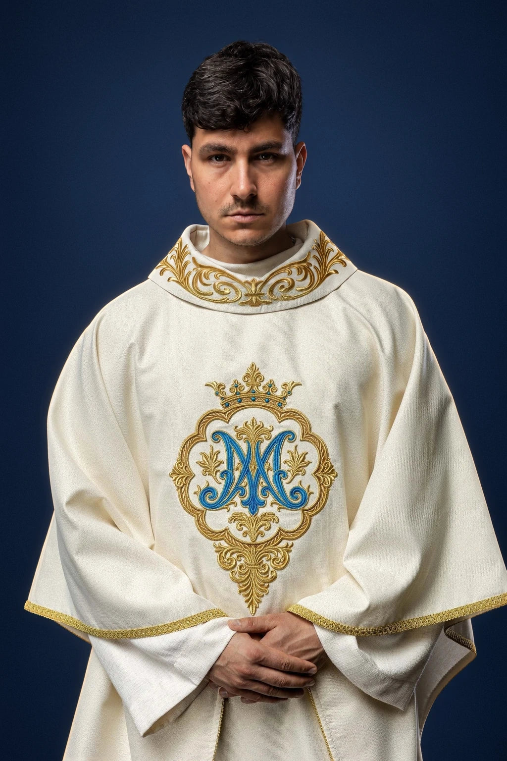 Front view of an ivory chasuble with gold trim and embroidered Marian monogram and crown on the chest