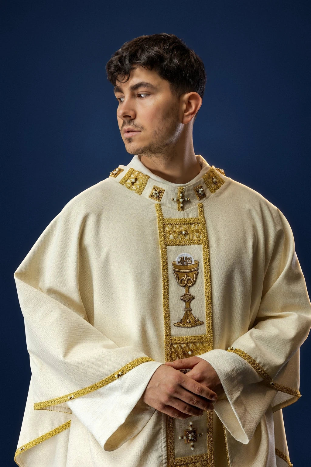 Front view of ivory chasuble with gold trim, jeweled collar, and chalice embroidered panel