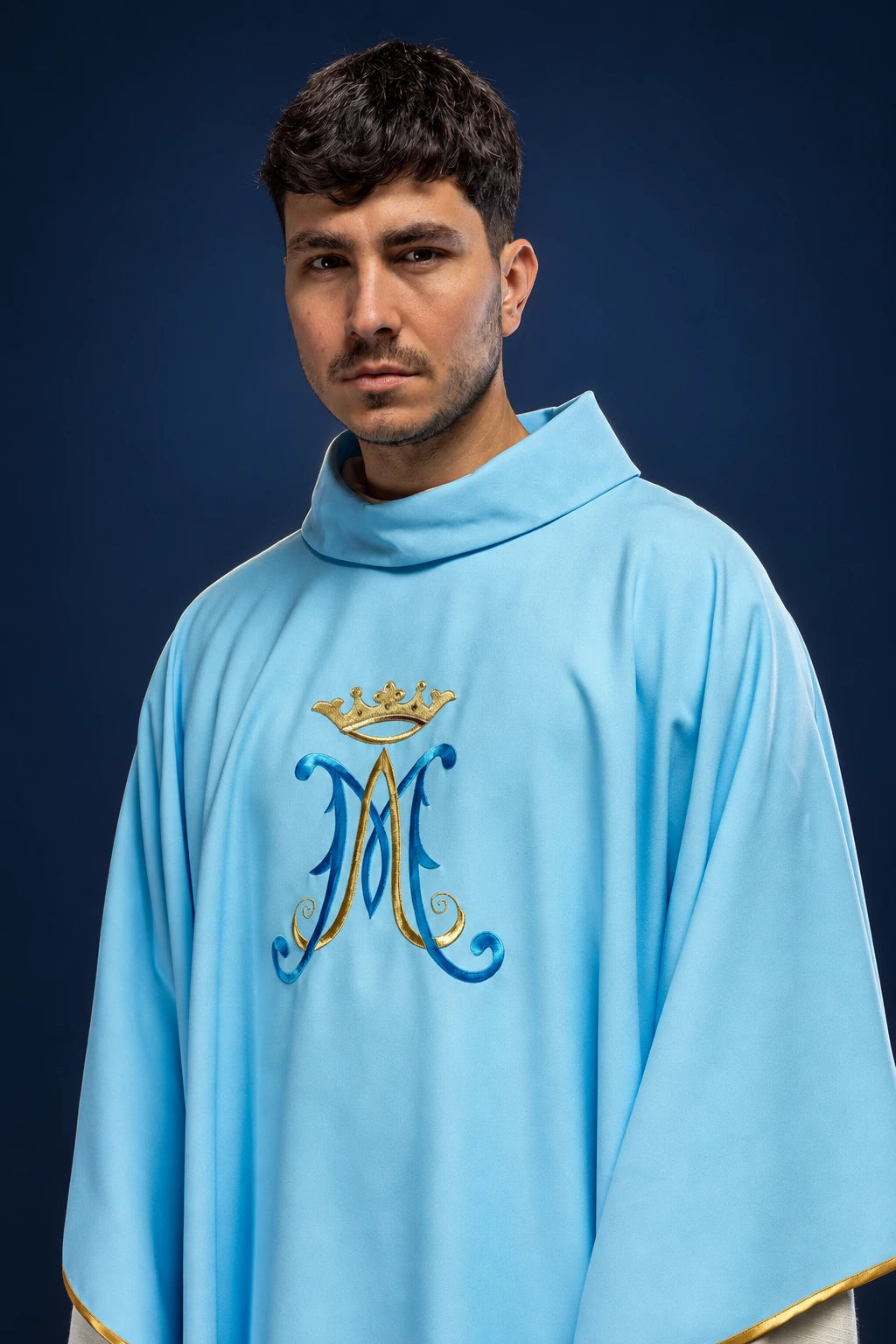 Front view of a light blue chasuble with embroidered Marian monogram and gold trim