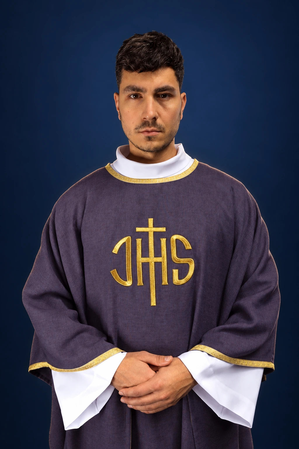 Front view of a purple chasuble with gold IHS embroidery and gold trim over a white alb