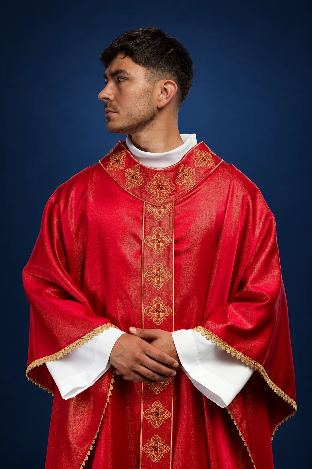 Front view of a red chasuble with embroidered gold orphrey and stone-set collar, worn over a white alb