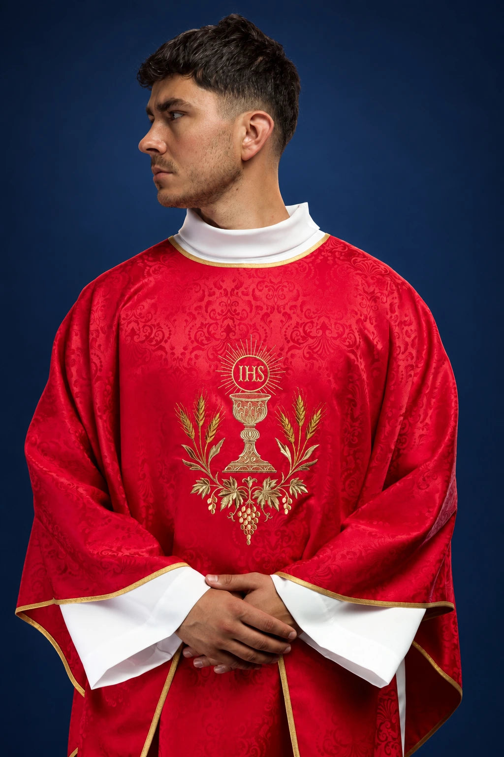 Front view of a red chasuble with gold chalice and IHS embroidery, edged in gold trim