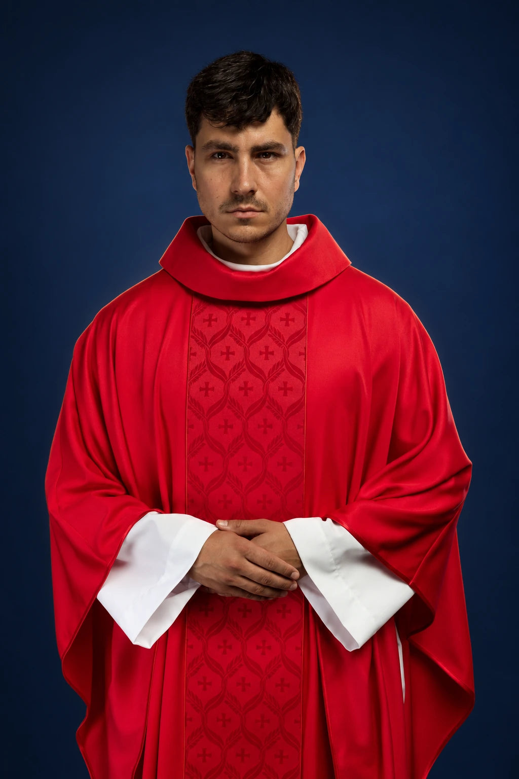 Front view of a red chasuble with a jacquard orphrey featuring crosses and wide draped sleeves