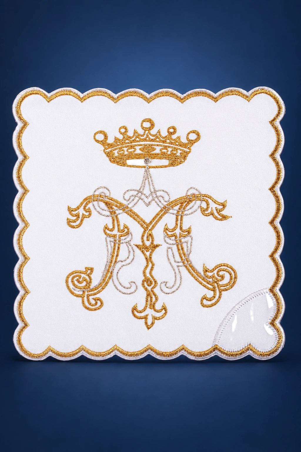 Front view of a white chalice pall with scalloped gold edge and embroidered Marian monogram topped by a crown