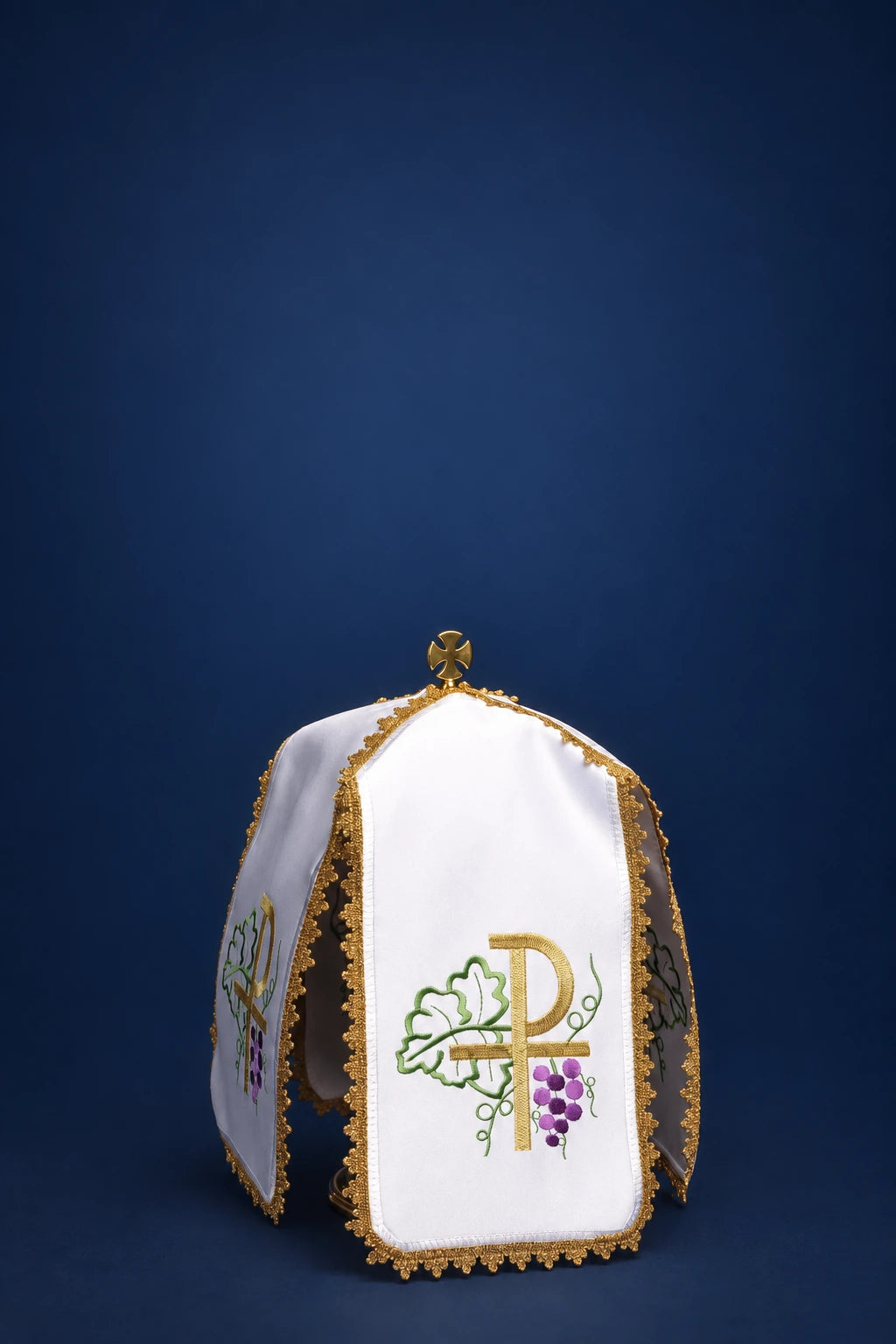 Front view of a white ciborium veil with gold trim and embroidered cross, vine, and grape motif