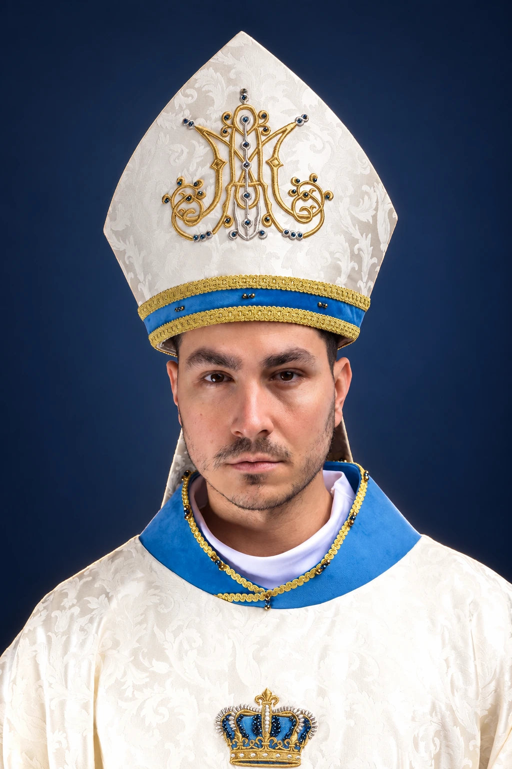 Front view of a white Marian miter and matching vestment, with gold embroidery and blue trim