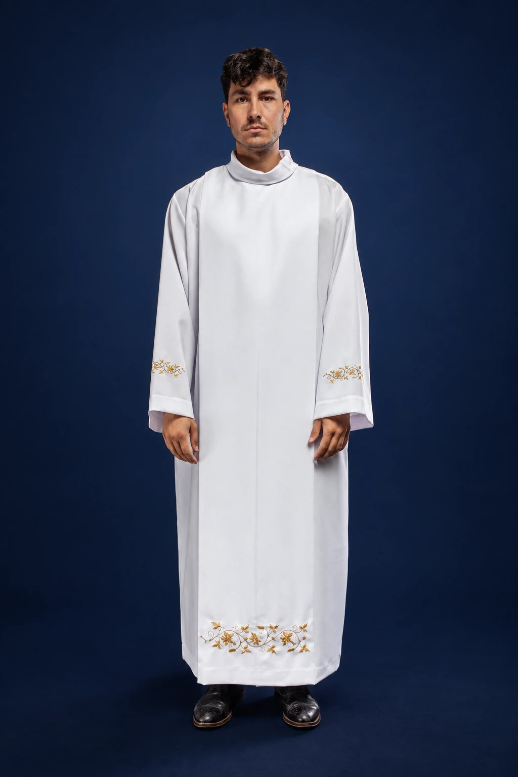 Front view of a white priest alb with stand-up collar, hood, and gold floral embroidery at the hem and cuffs