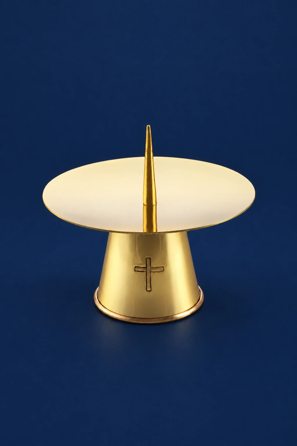 Gold-colored brass candlestick with cross detail and round drip plate, front view