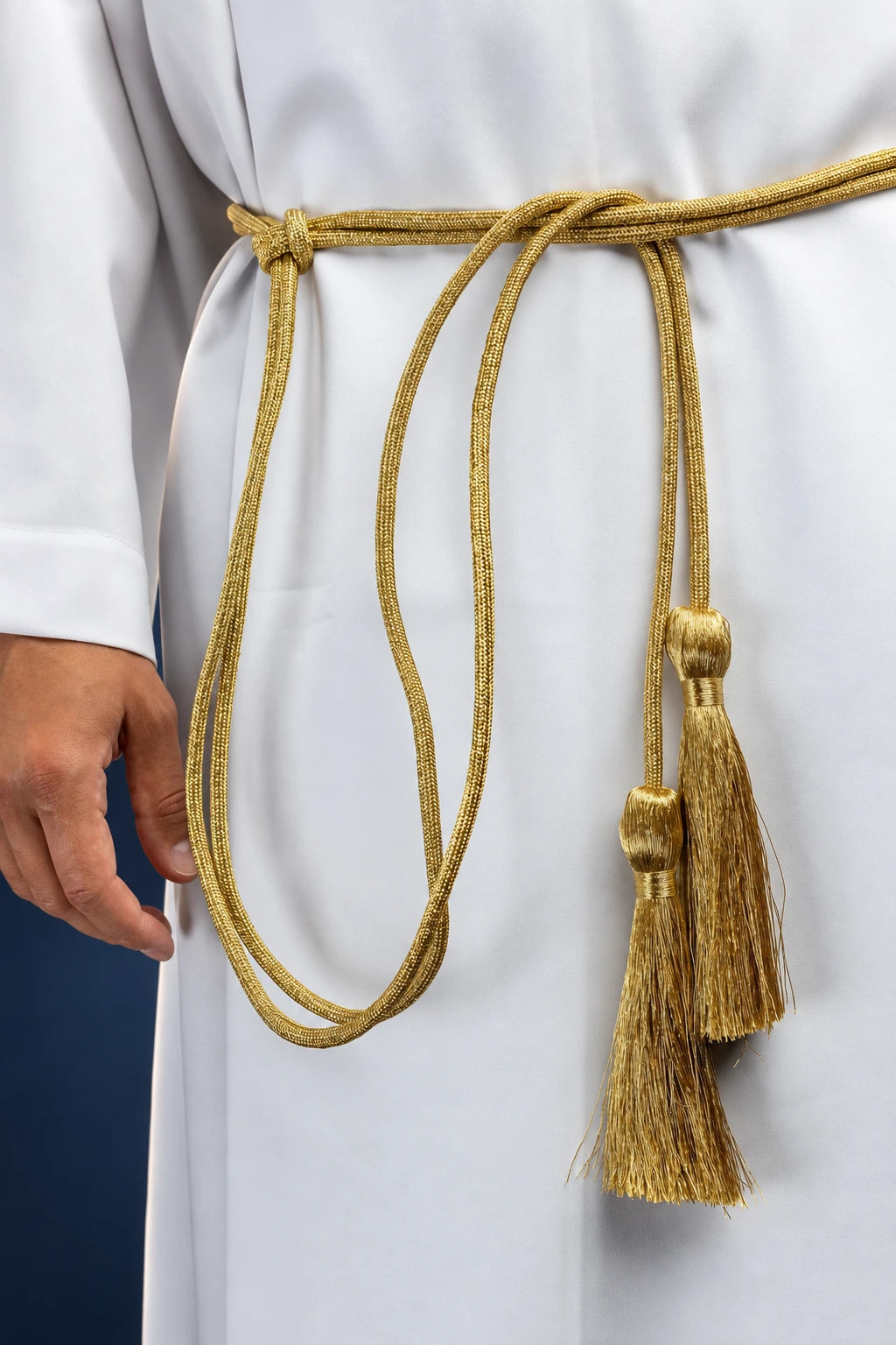 Gold liturgical cincture tied at the waist, with hanging cords and tassel ends on a white robe