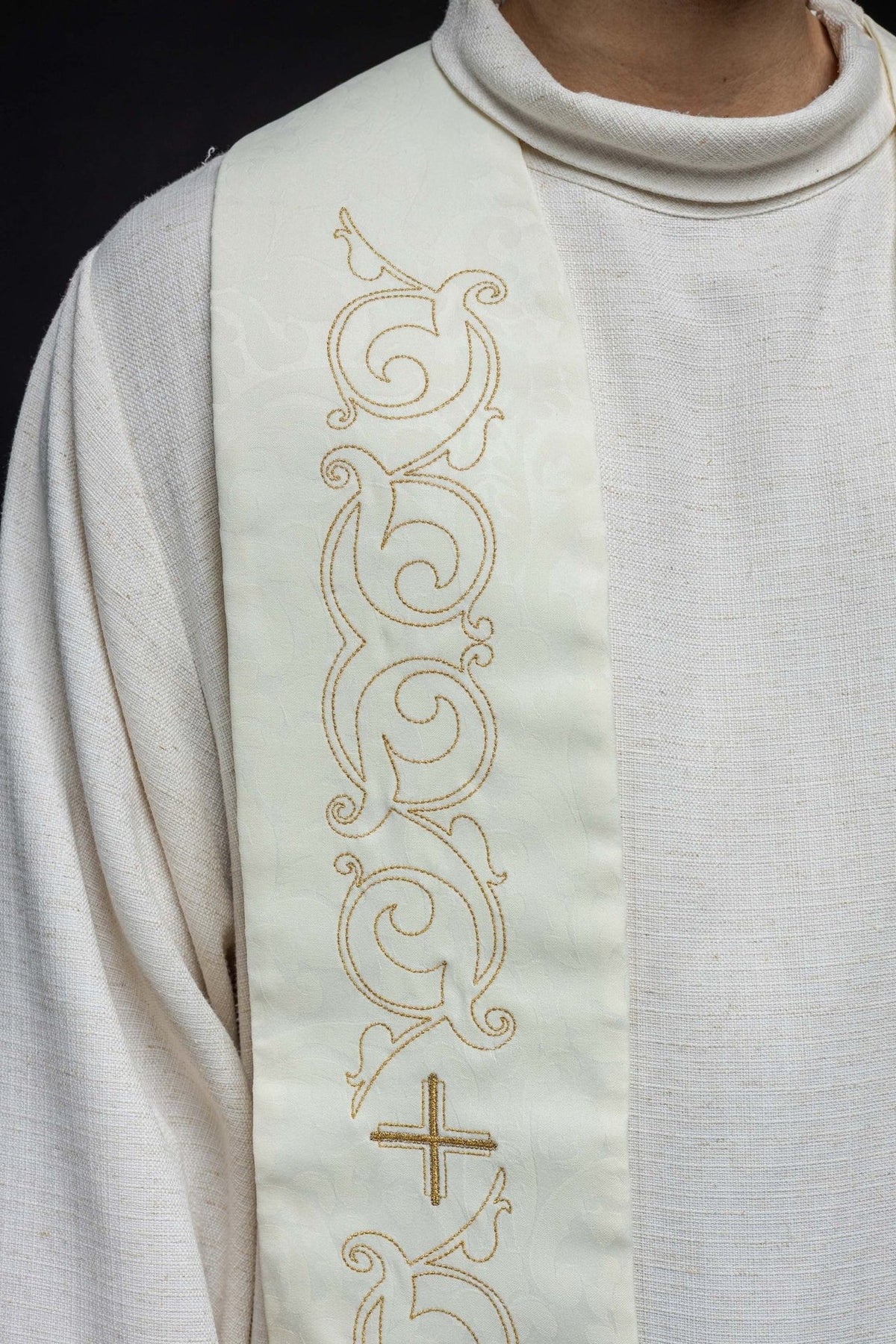 Roman stole close-up showing ecru jacquard fabric and gold scroll embroidery
